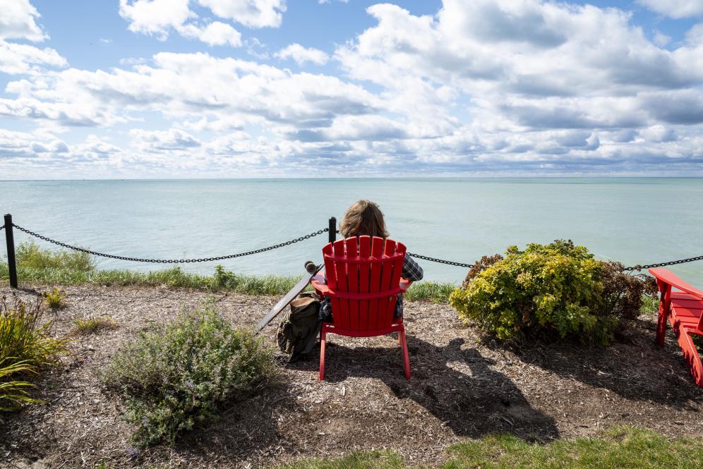 A student lounges in a red chair along Lake Michigan.